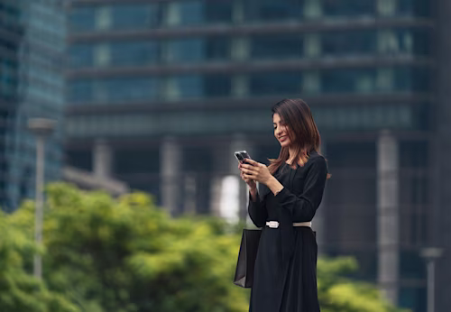 woman in a black dress uses a phone