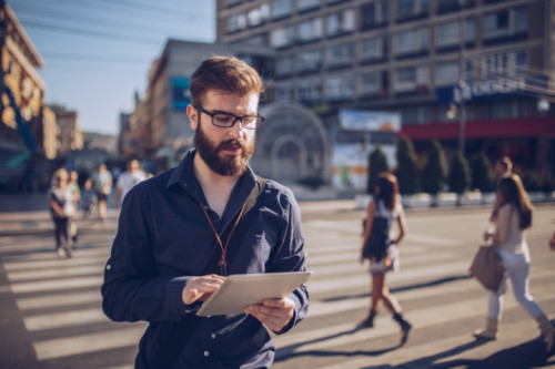 Homem segurando um tablet e andando na rua