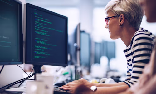 Profile view of young female programmer working on computer software in the office