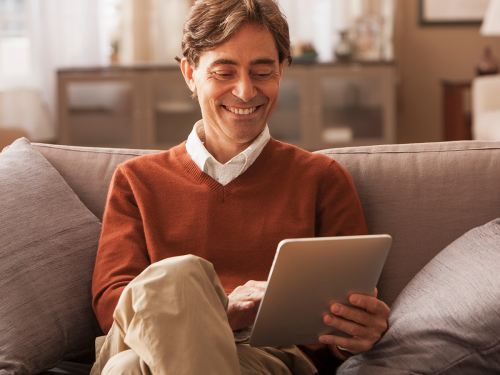 a man looking at the tablet on the sofa