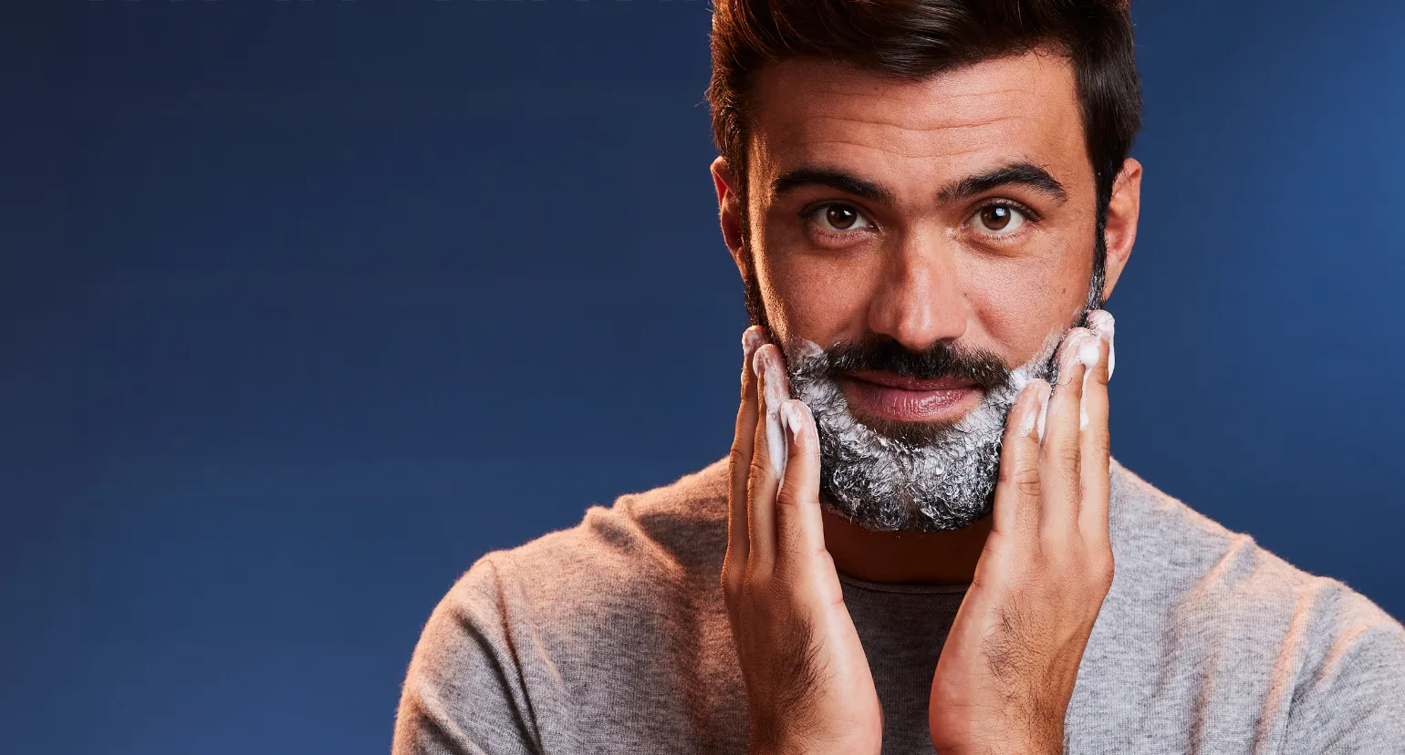 Persona aplicando champú en la barba con las manos, ilustrando beneficios del champú para barba.