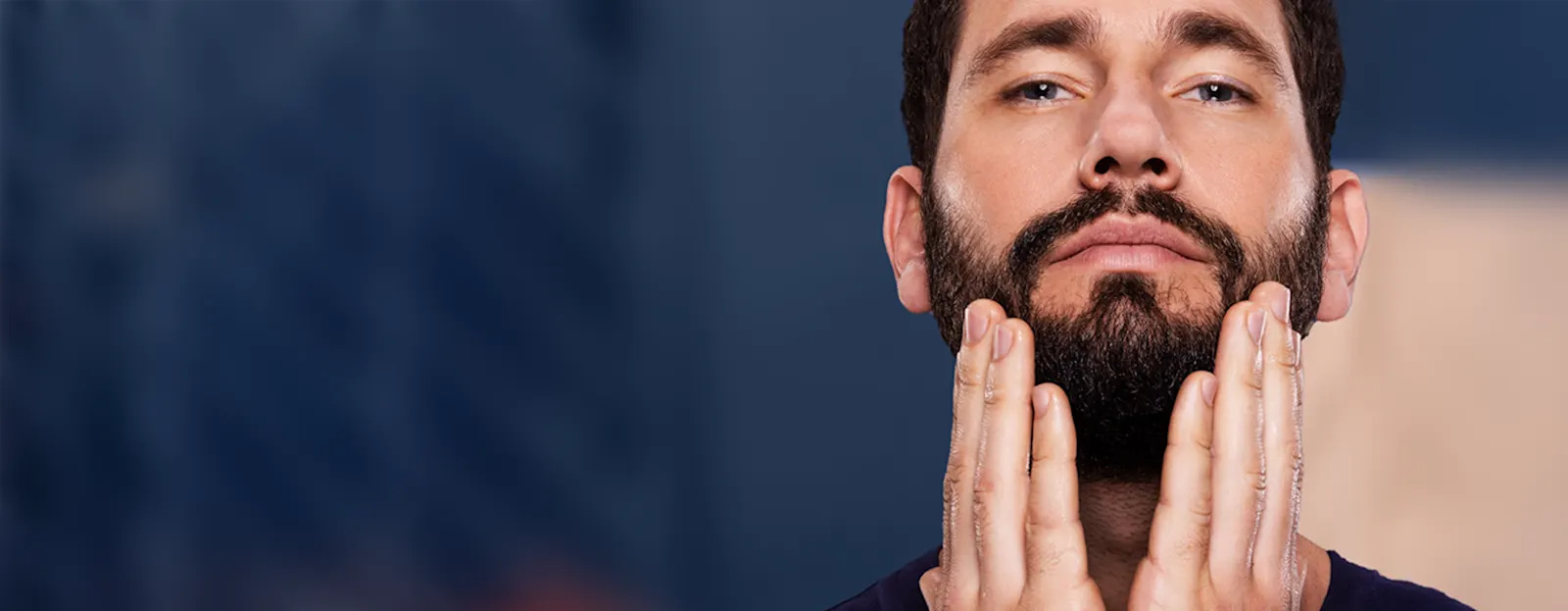 Primer plano de una persona con barba tocándola con ambas manos, mostrando el tema de la caspa en la barba.