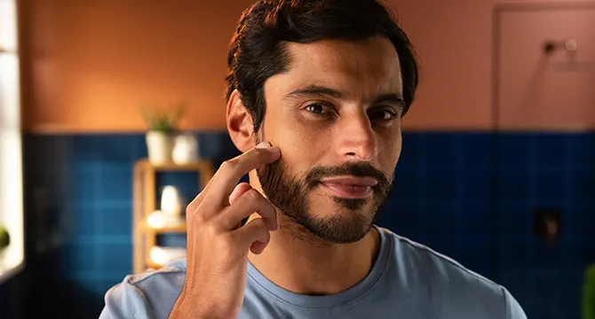 Un hombre aplicando gel de afeitar transparente en la cara.