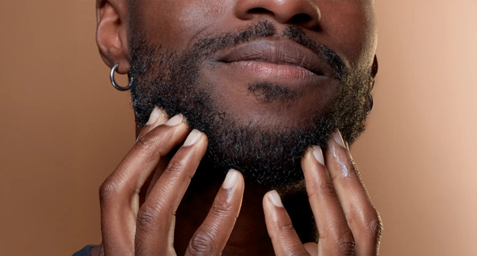 Primer plano de una persona tocando su barba con ambas manos, ilustrando la caspa de barba.