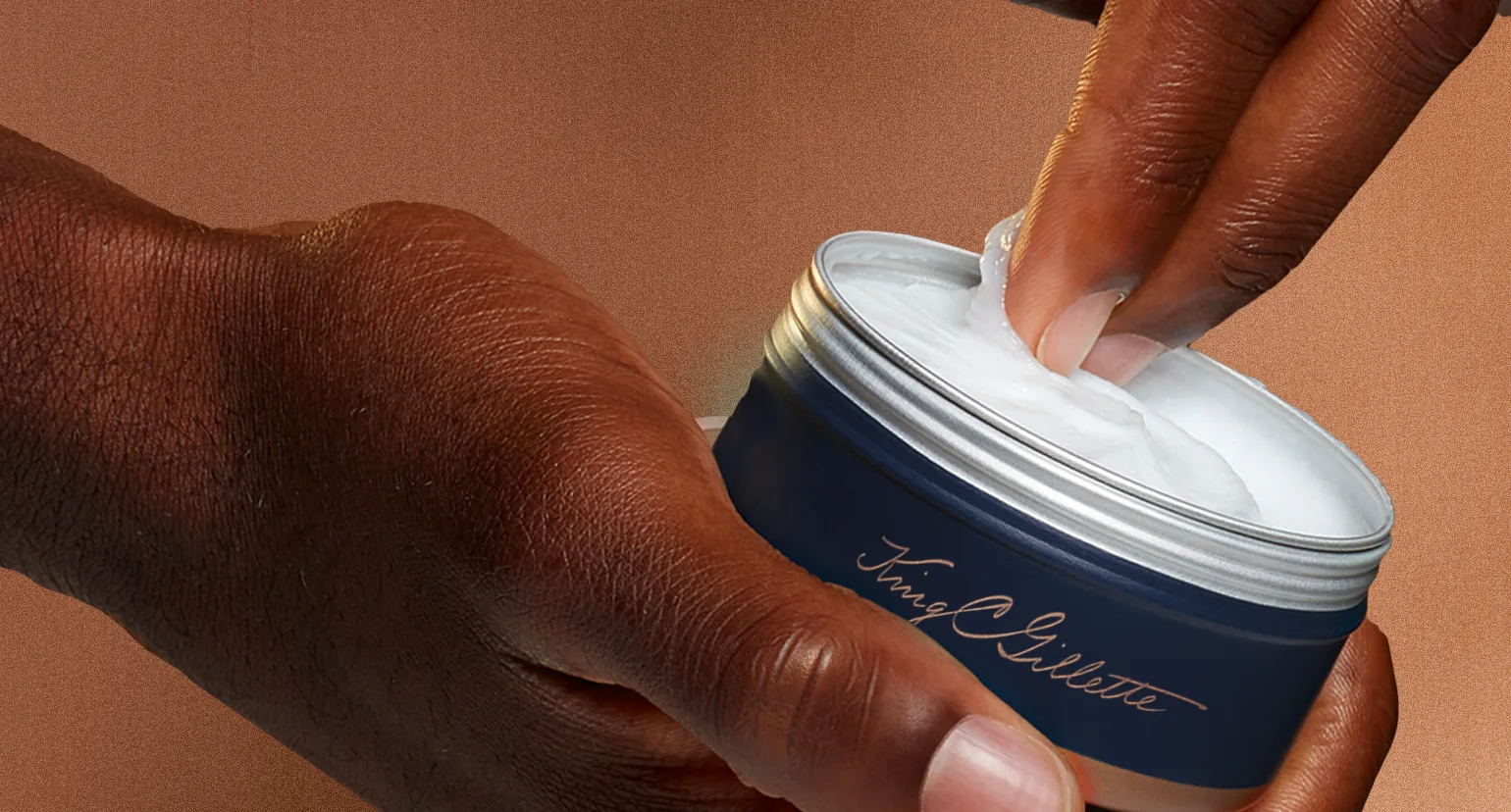 Bálsamo para barba King C Gillette siendo sacado de un envase con la mano.