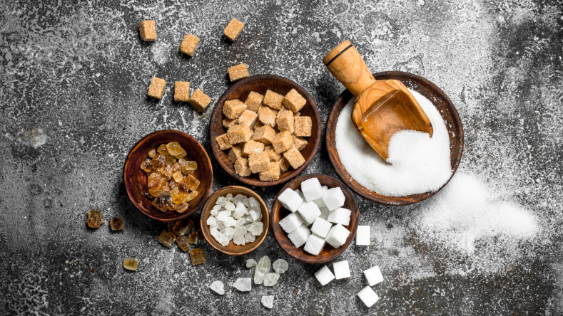 white sugar, brown sugar, and sugar cubes in wooden bowls