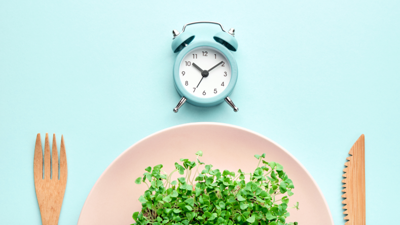 Plate of greens and a clock on a baby blue background