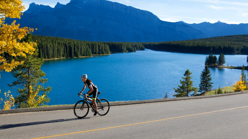 Woman on a road bike with a lake and mountains in the background