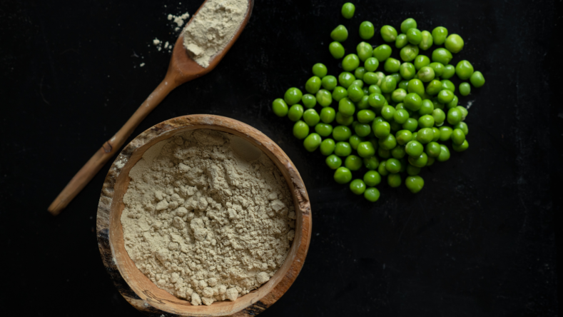 Green peas and pea protein in a bowl on a black background