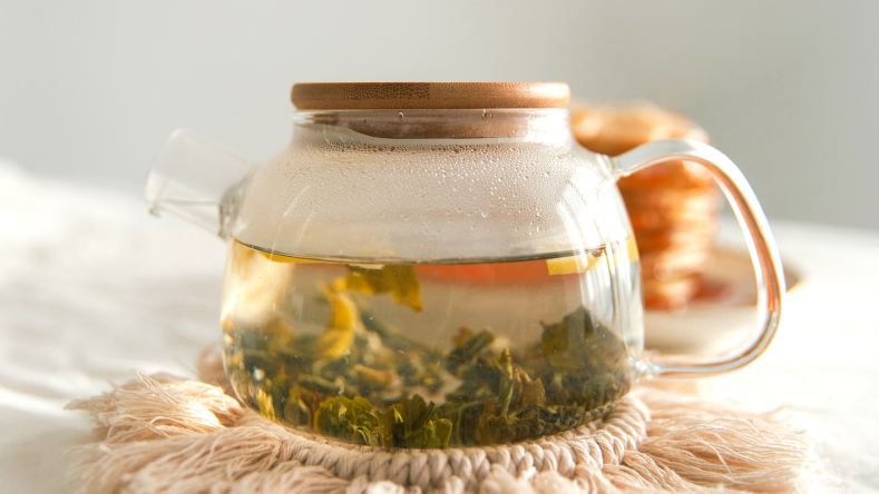 green tea steeping in a glass kettle 