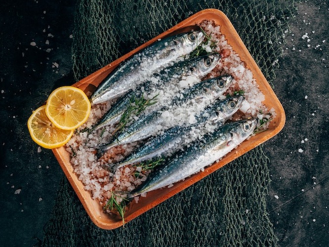 4 sardines covered in salt on a black background