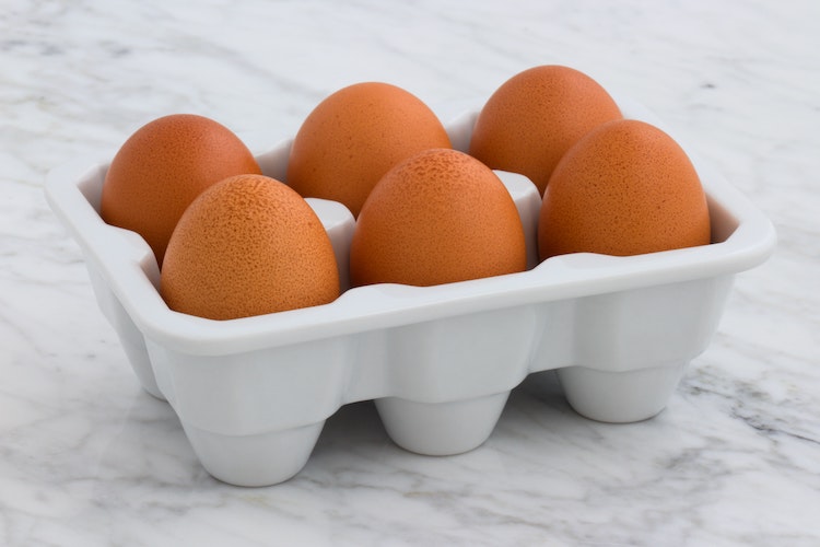 6 eggs in a porcelain carton on a marble background