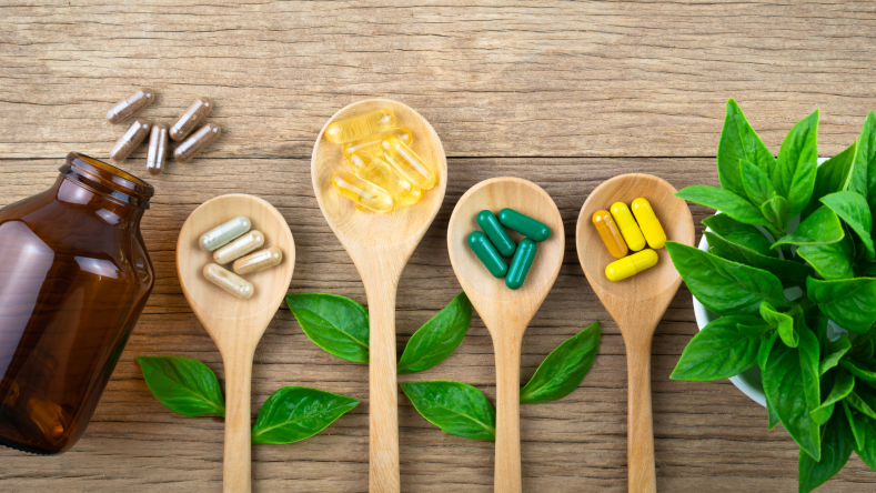 Herbal supplements in a jar and on wooden spoons