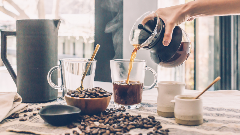 Pouring black coffee into clear mugs