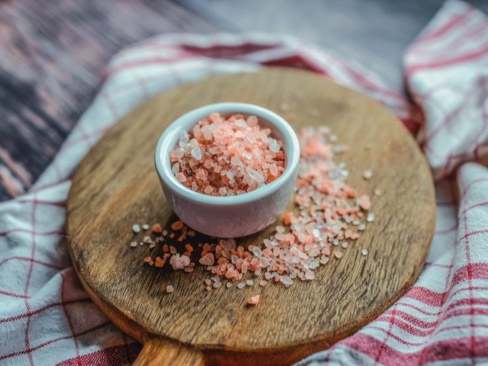 Pink salt in a white ramekin on a wooden chopping board