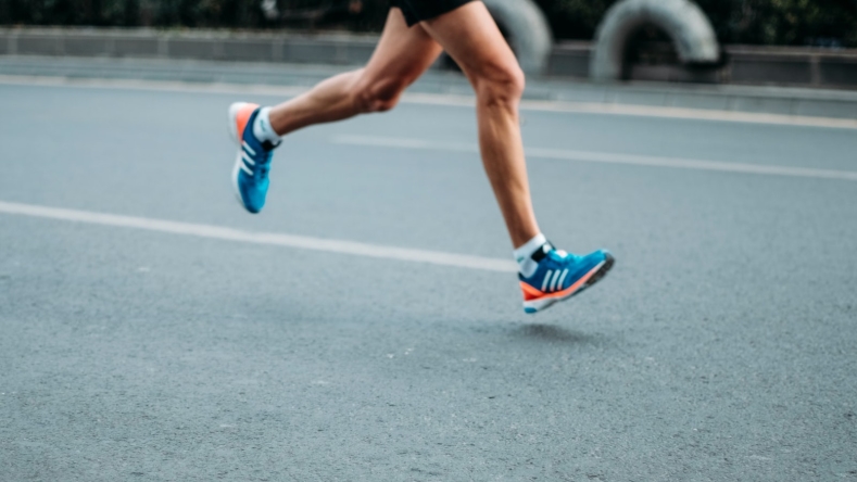 person with blue sneakers running on pavement