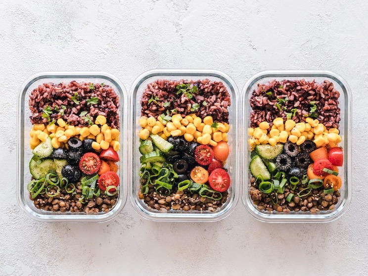 3 vegan burrito bowls in clear rectangle containers on a gray background