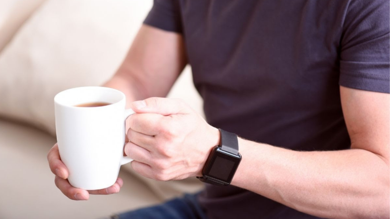 man holding a white coffee cup