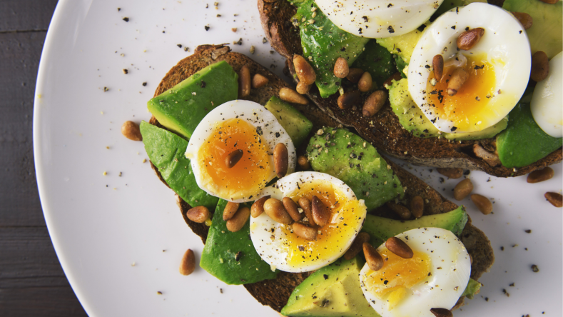Soft-boiled eggs, avocado and pine nuts on rye toast