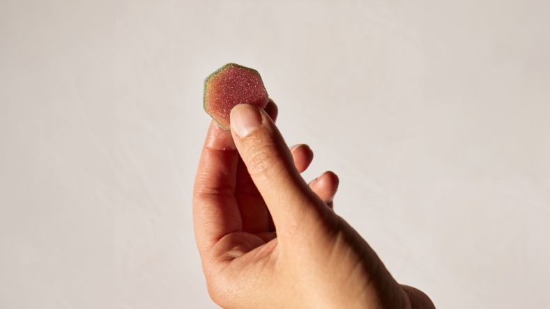 hand with gummy in front of a neutral wall