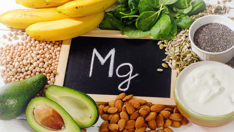 Mg written on a chalkboard surrounded by avocado, almonds, spinach and bananas