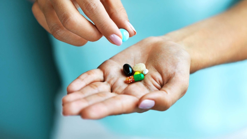woman holding a variety of supplements