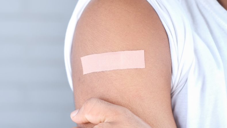 person with a rectangle bandage on arm against a light background