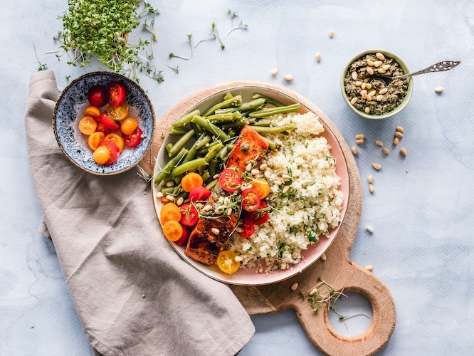 Rice bowl with salmon, rice, green beans and cherry tomatoes, on a gray background