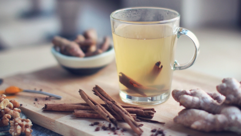Cinnamon tea on cutting board in glass cup with cinnamon sticks and ginger 