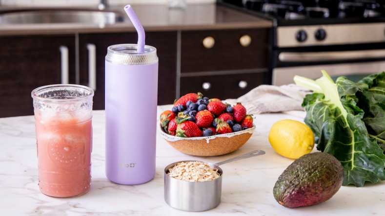 Smoothie, drink bottle, berries and kale on a marble counter