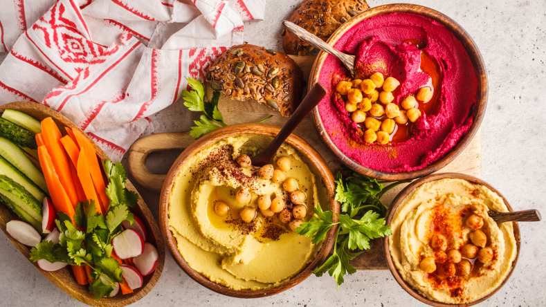 assortment of colorful hummus recipes with veggies and bread