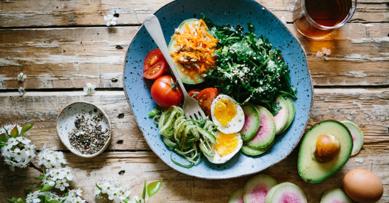 hard-boiled eggs in a bowl with avocado, tomatoes, and kale