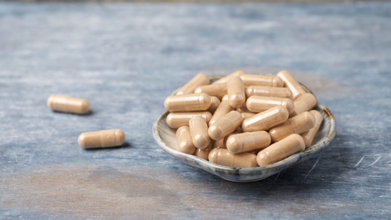 Ashwagandha pills in a stone dish on a blue background