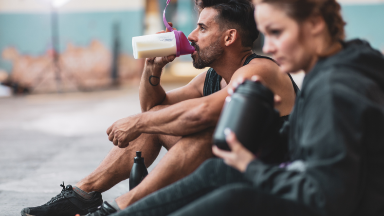 A man and a woman drinking protein shakes