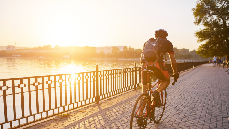 Cyclist wearing a backpack riding on a bike path