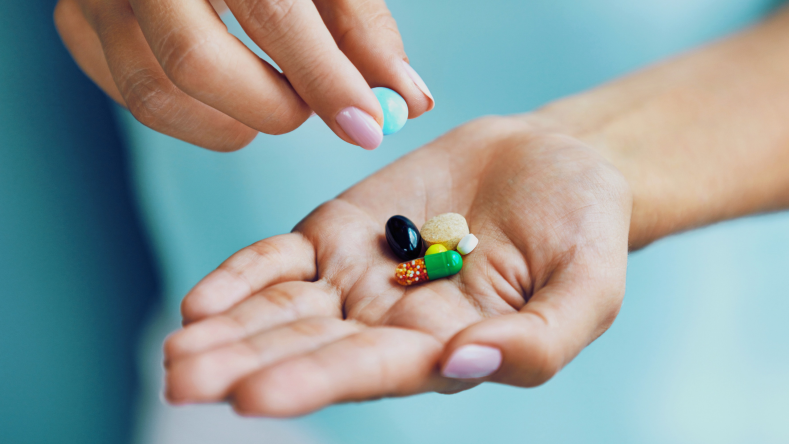 hand holding a variety of supplement forms