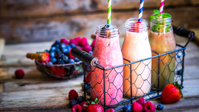 three smoothie recipes in individual jars with striped straws