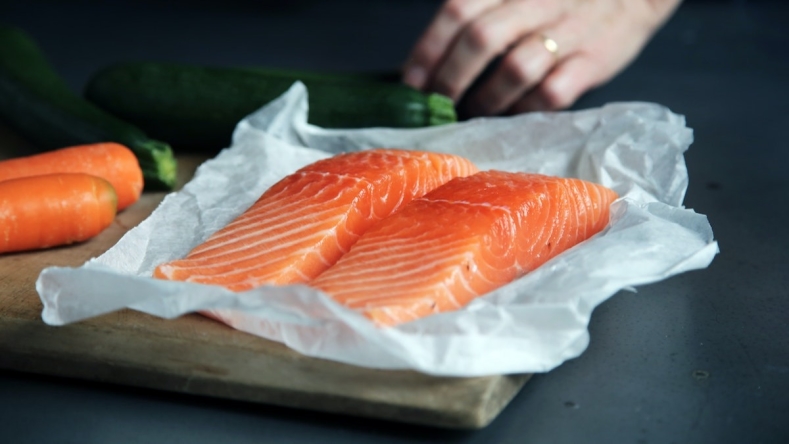 2 salmon filets on parchment paper on a wooden chopping board