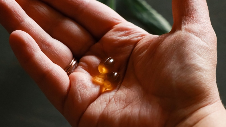 hand with ring holding vitamin capsule