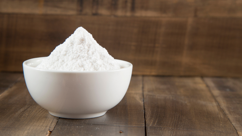 Sodium bicarbonate in a white bowl on a wooden background