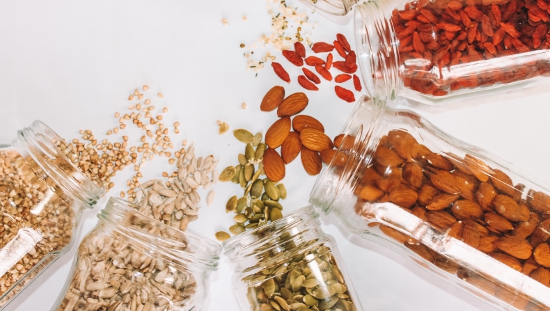 Seeds in jars spilled on counter top (almonds, pumpkin, sunflower, hemp, buckwheat)