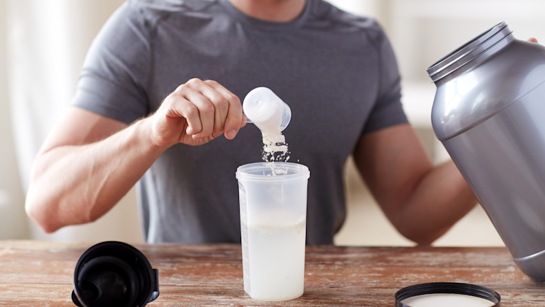 Man scooping creatine powder into water bottle