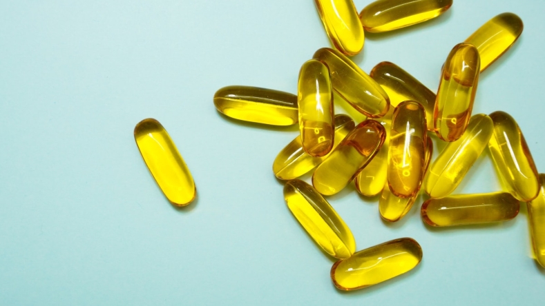 yellow supplement pills against a light blue background