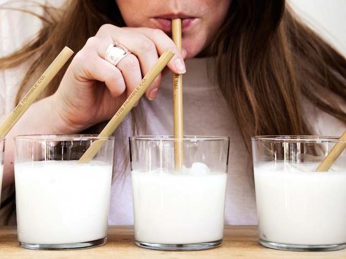 Woman sipping glass of milk through a straw