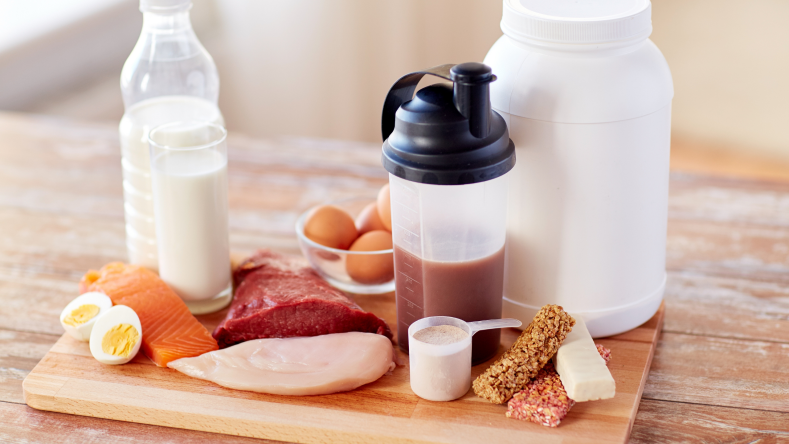 Eggs, salmon, chicken, milk and protein powder on a wooden countertop