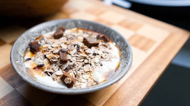 Bowl of oatmeal topped with dried figs, on a wooden table