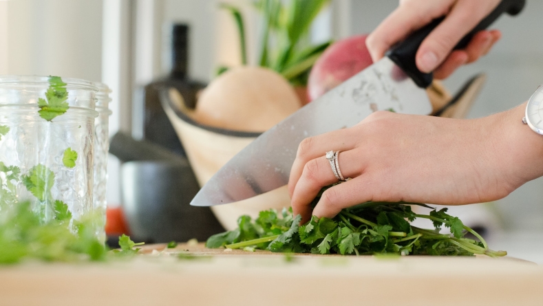 woman chopping cilantro on cutting board