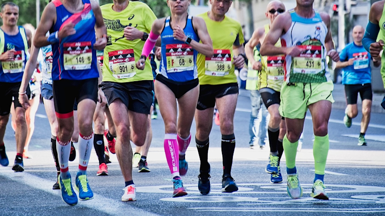 men and women running a race along a paved road