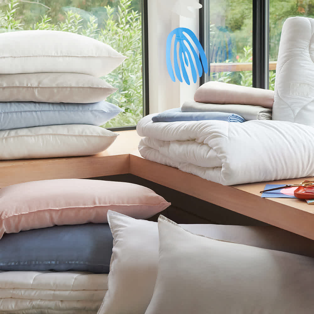Pile of pillows in blush, blue, gray, and white pillowcases