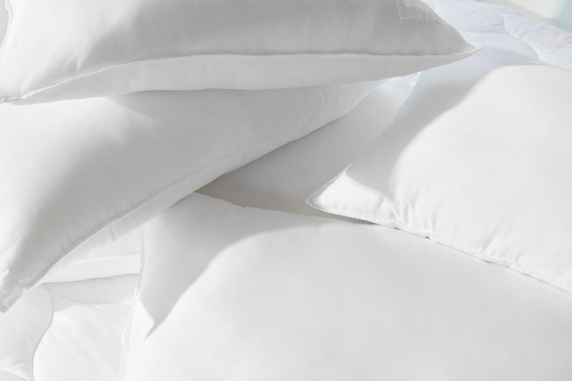 Close crop of a messy stack of white pillows.